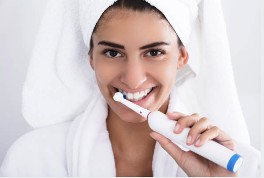 Imagen de persona sonriente sosteniendo un cepillo de dientes y enjuague bucal, representando los cuidados posteriores al blanqueamiento dental